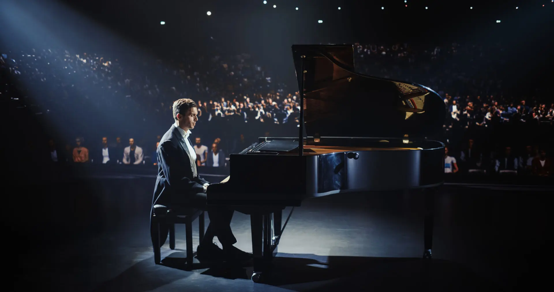 Pianist performing on stage in spotlight.
